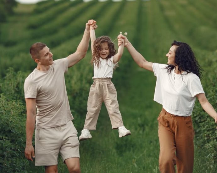 Joyful family moment in a green field during summer, capturing love and playfulness.