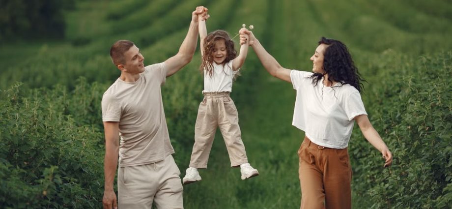 Joyful family moment in a green field during summer, capturing love and playfulness.